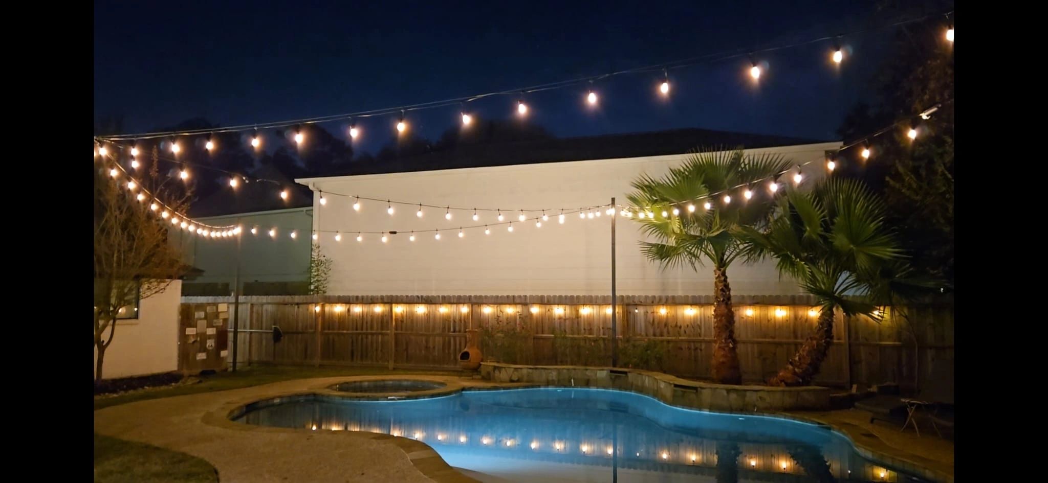 Luxury pool with overhead string lights and shade sail