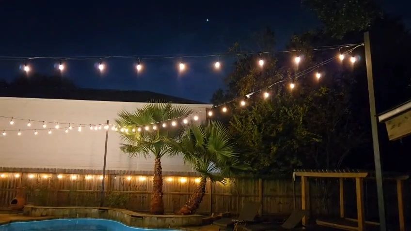 Backyard pool with warm bistro string lights